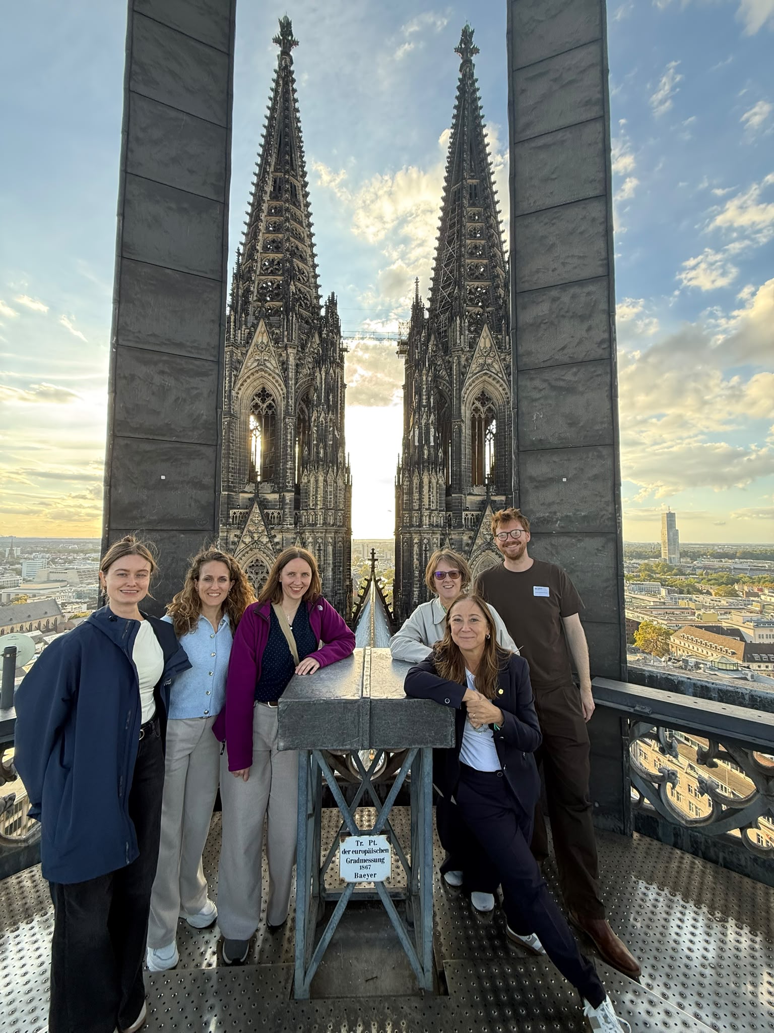 Some of the meeting attendees standing on the roof of Cologne Cathedral with a few of the city behind them