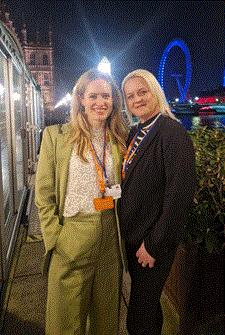 Rare Disease Day House of Commons 2026 Elizabeth Forsythe in green trouser suit and Kerry Leeson Beevers in black trousers suit both with blonde hair on the terrace at the Houses of Parliament with the London Eye in the background