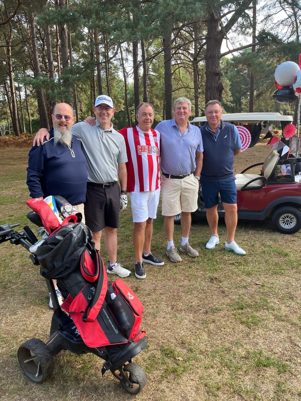 five male golfers posing with the captain on the golf course